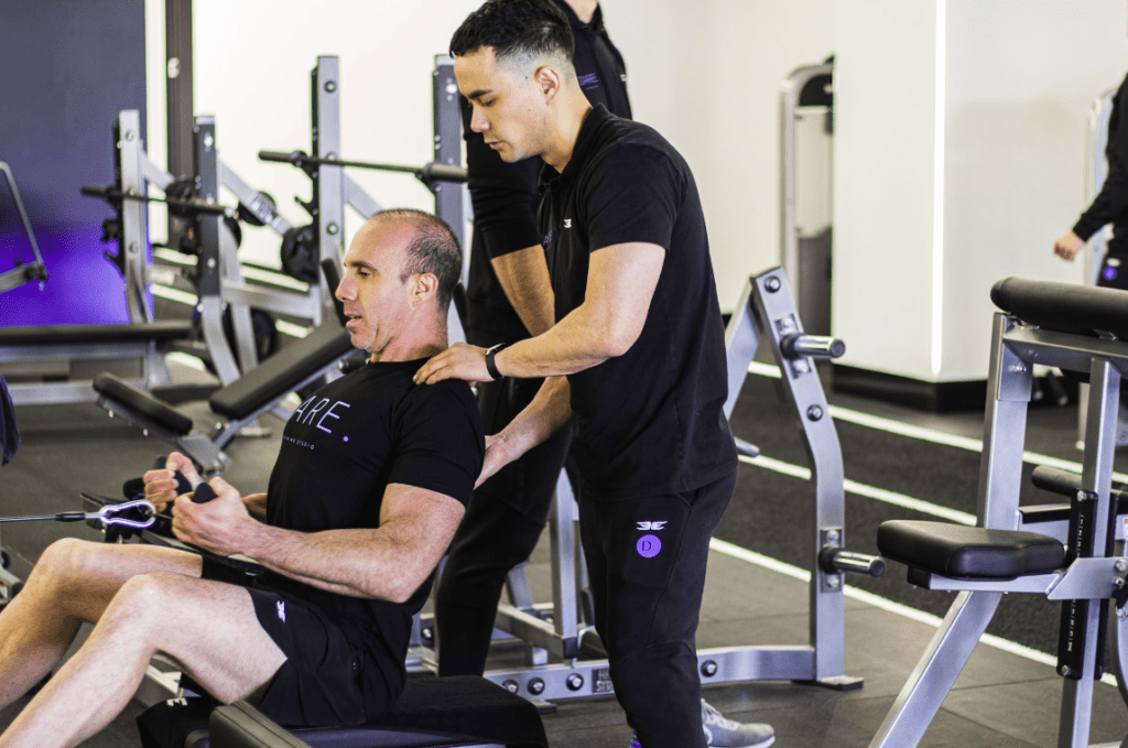 personal trainer assisting with seated row